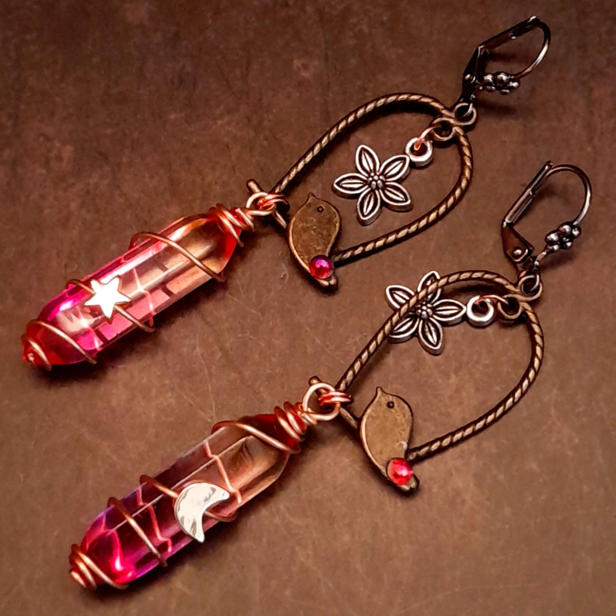 bird earrings with dangling flower and glass drops that change color from yellow to pink. wire wrapped with a moon and star
