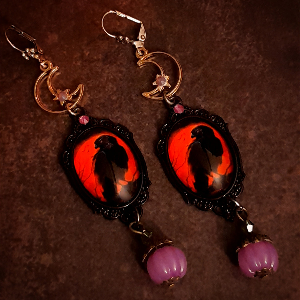 Handmade witchy crow earrings with crescent moons, stars, smoky purple Swarovski crystals, red crow cabochons, and hidden fairy details, Victorian style and vintage style magical fantasy jewelry by Rachel Flam Design