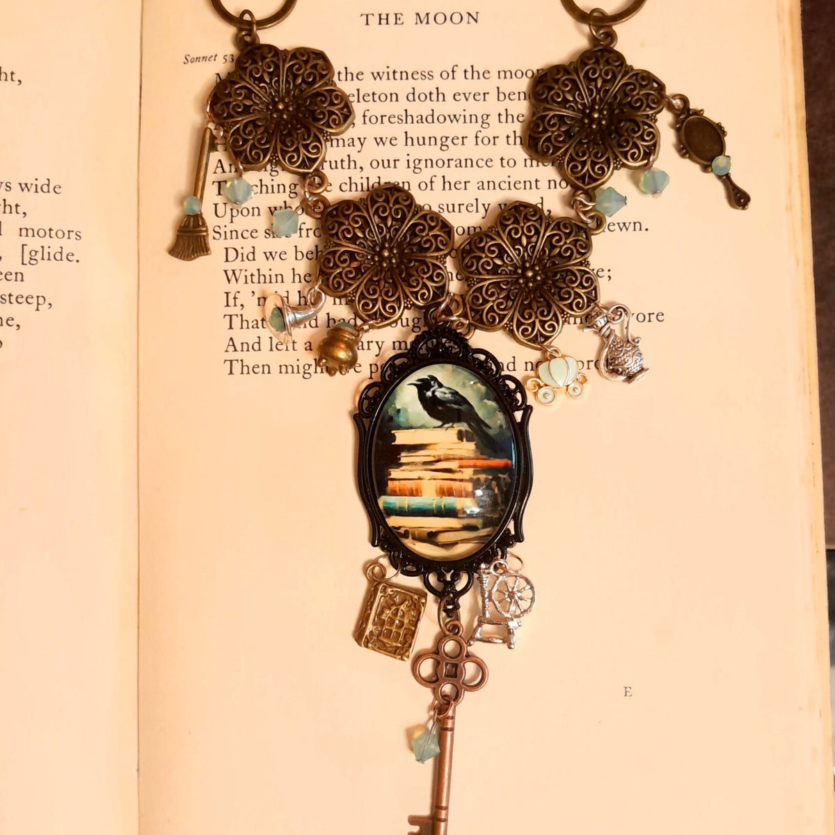 Closeup of black crow perched on stacked books cabochon centerpiece, Victorian style vintage style necklace with Swarovski crystals, Rachel Flam Design