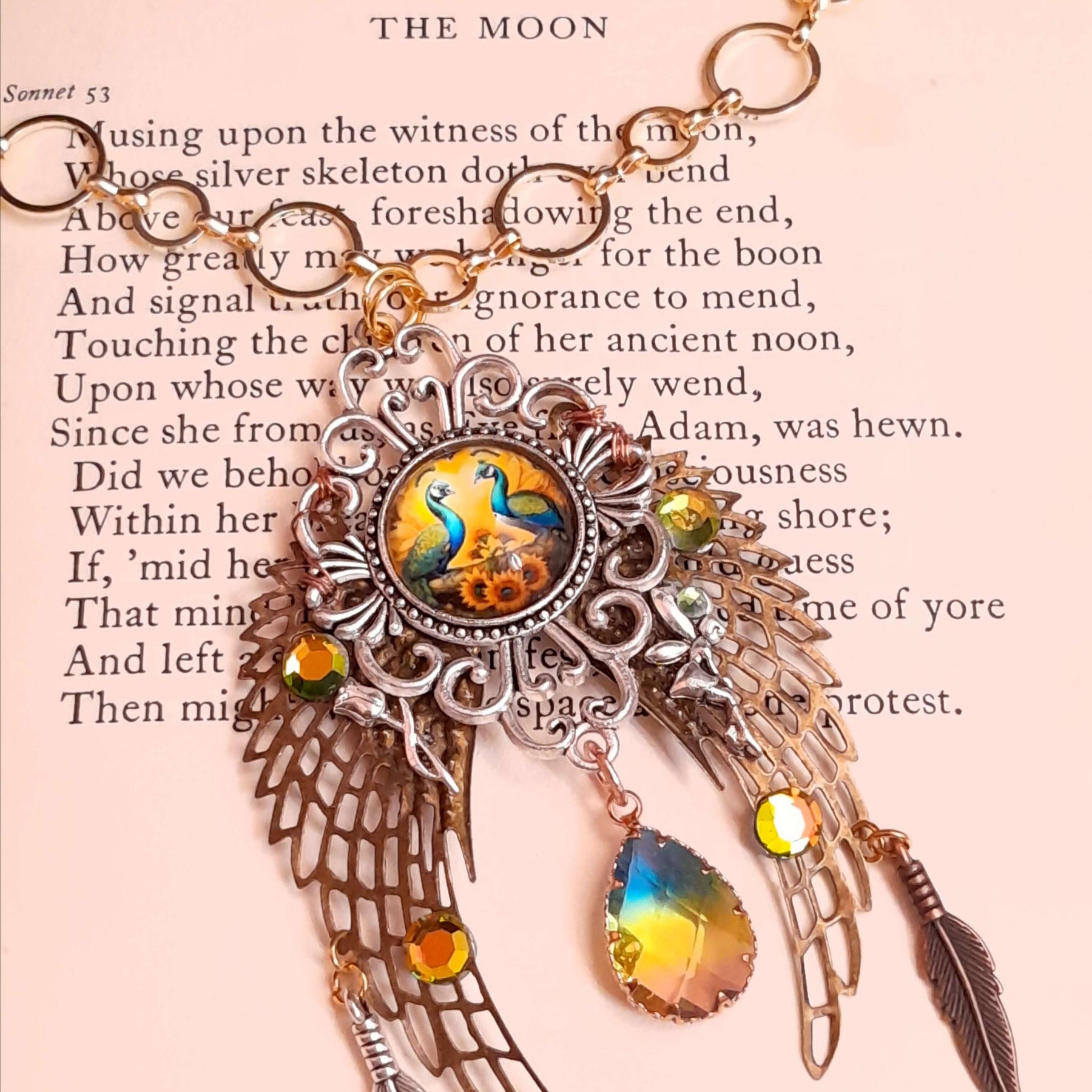 victorian style necklace with a peacock cabochon. Bright golden yellow and green crystals. Feather accents, a fairy, and a striking teardrop crystal