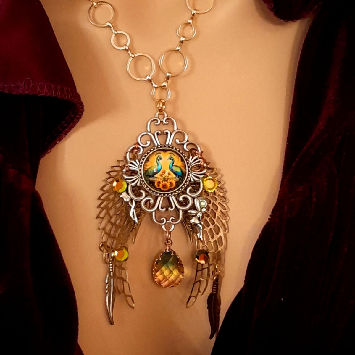 victorian style necklace with a peacock cabochon. Bright golden yellow and green crystals. Feather accents, a fairy, and a striking teardrop crystal