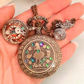 Alice in Wonderland pocket watch necklace held in hand showing Alice silhouette with multicolor Swarovski crystals White Rabbit and teacup charms antiqued brass Victorian style vintage style fantasy handmade