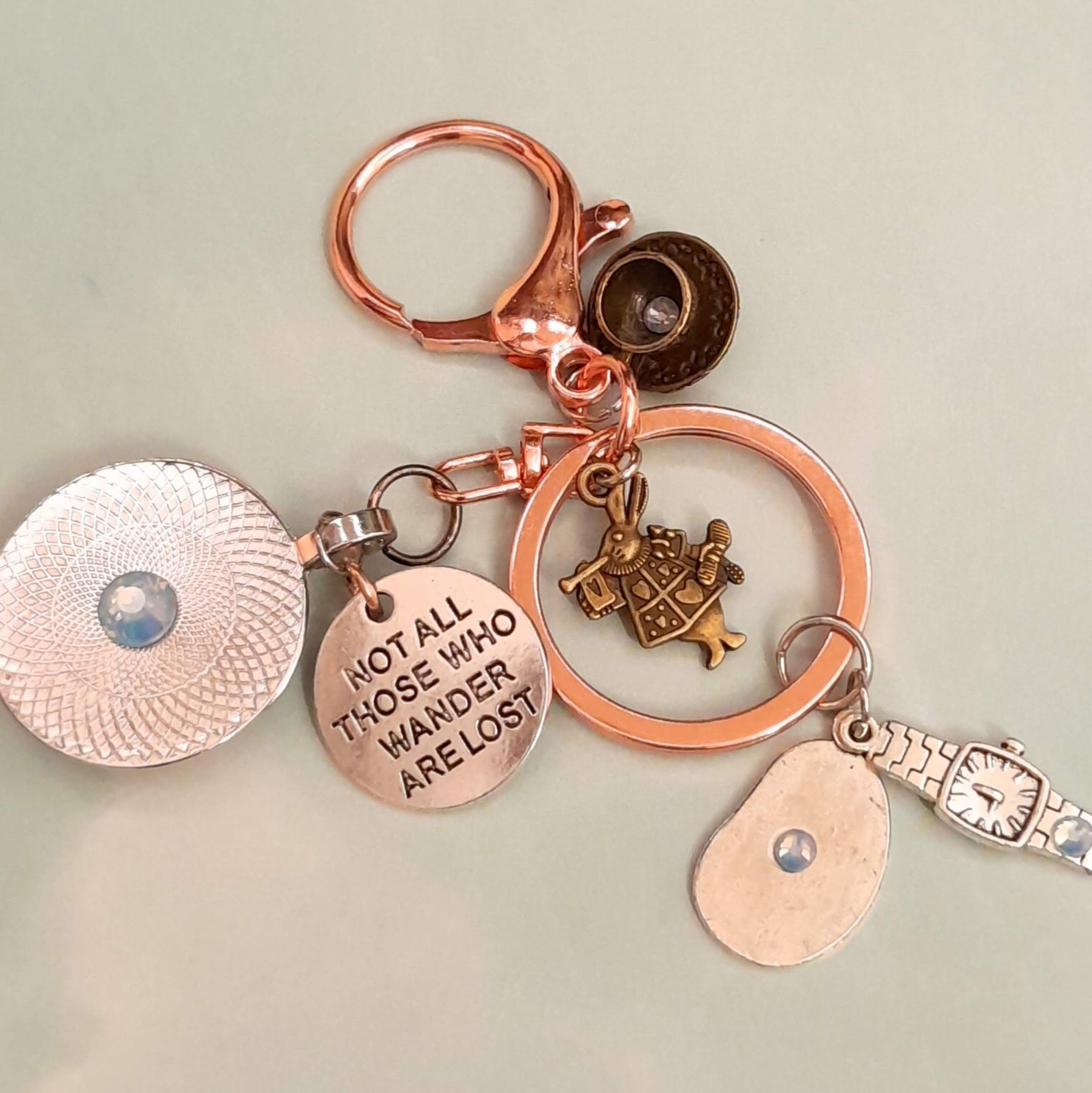 Alice in Wonderland fantasy purse charm and keychain back view with round textured disc with Swarovski crystal center, "Not All Those Who Wander Are Lost" disc, White Rabbit figurine, melting clock teardrop, and wristwatch charm — Victorian style vintage style