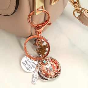 Alice in Wonderland fantasy purse charm and keychain clipped to zipper with White Rabbit clock face cabochon, "Not All Those Who Wander Are Lost" disc, White Rabbit figurine, and wristwatch charm — Victorian style vintage style