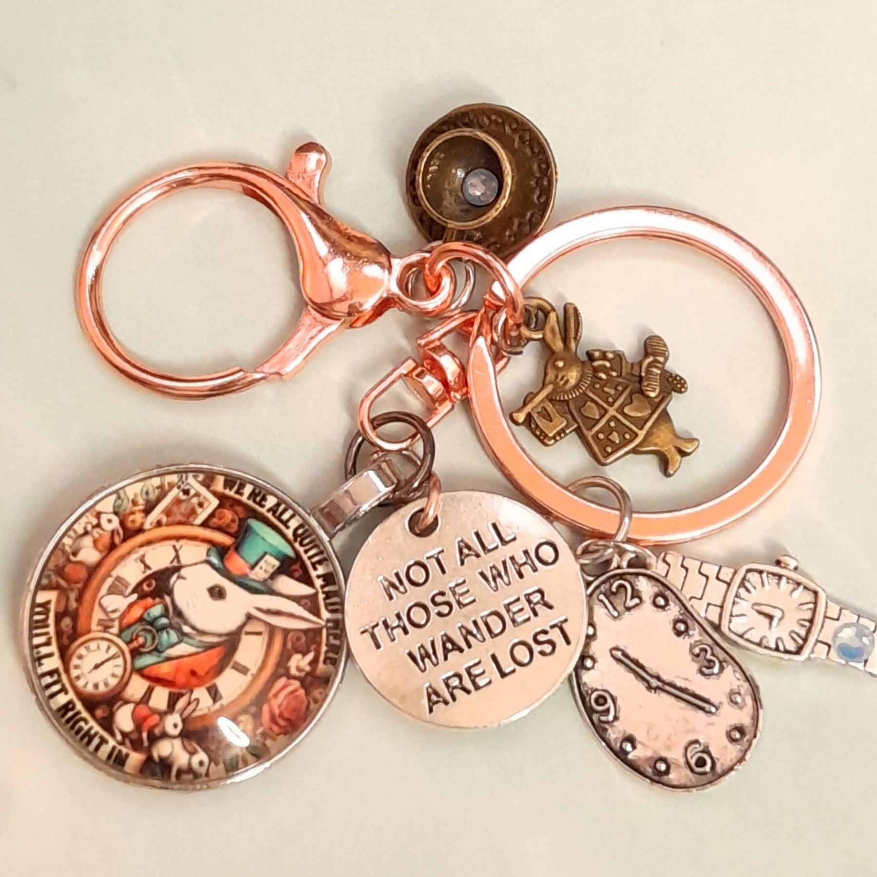 Alice in Wonderland fantasy purse charm and keychain with White Rabbit clock face cabochon, "Not All Those Who Wander Are Lost" disc, melting clock teardrop, wristwatch charm, White Rabbit figurine, and round textured button charm — Victorian style vintage style