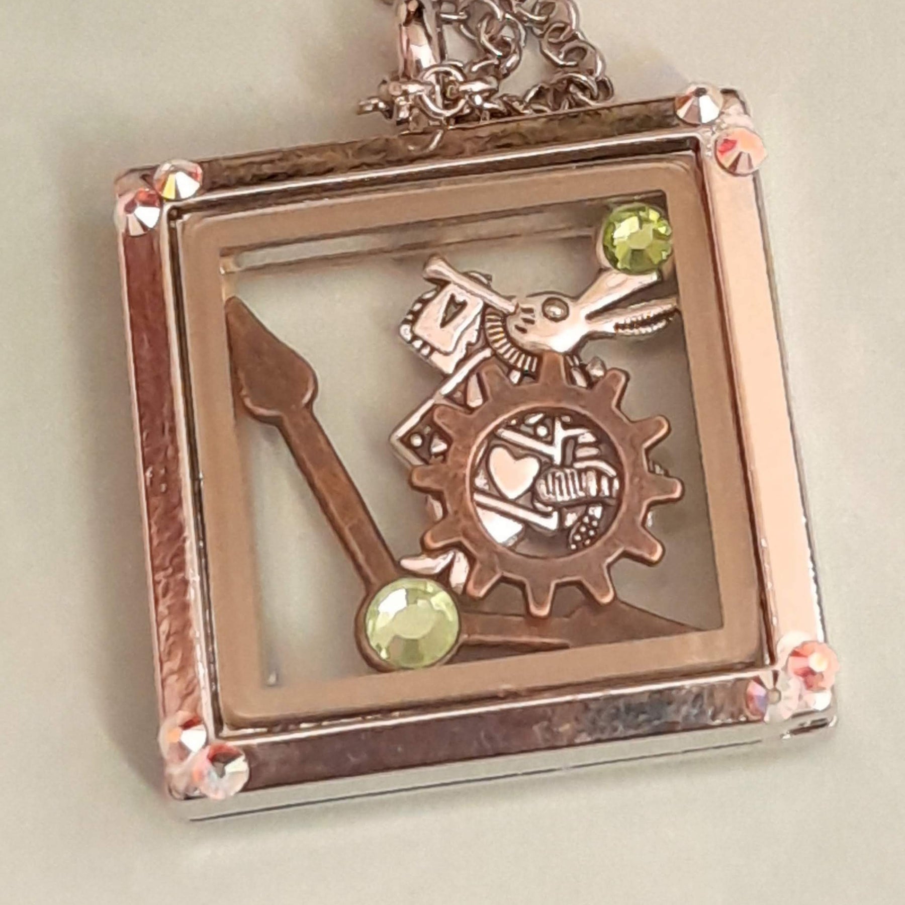 Magical fantasy Alice in Wonderland square locket necklace back view showing  with White Rabbit and gear charms, green Swarovski crystal corner accents,  chain, Victorian style vintage style
