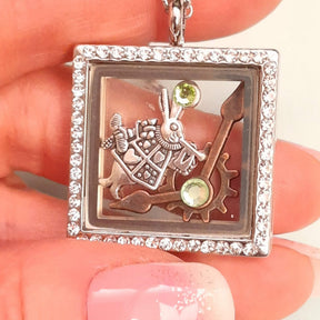 Handmade magical fantasy Alice in Wonderland square locket necklace held in hand showing full Swarovski crystal border, White Rabbit and clock hand charms inside, green crystal accents, Victorian style vintage style