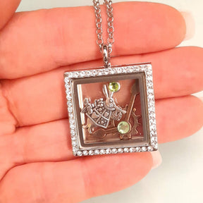 Handmade magical fantasy Alice in Wonderland square locket necklace held in palm showing size, Swarovski crystal border, White Rabbit and clock hand charms inside, green crystal accents, Victorian style vintage style