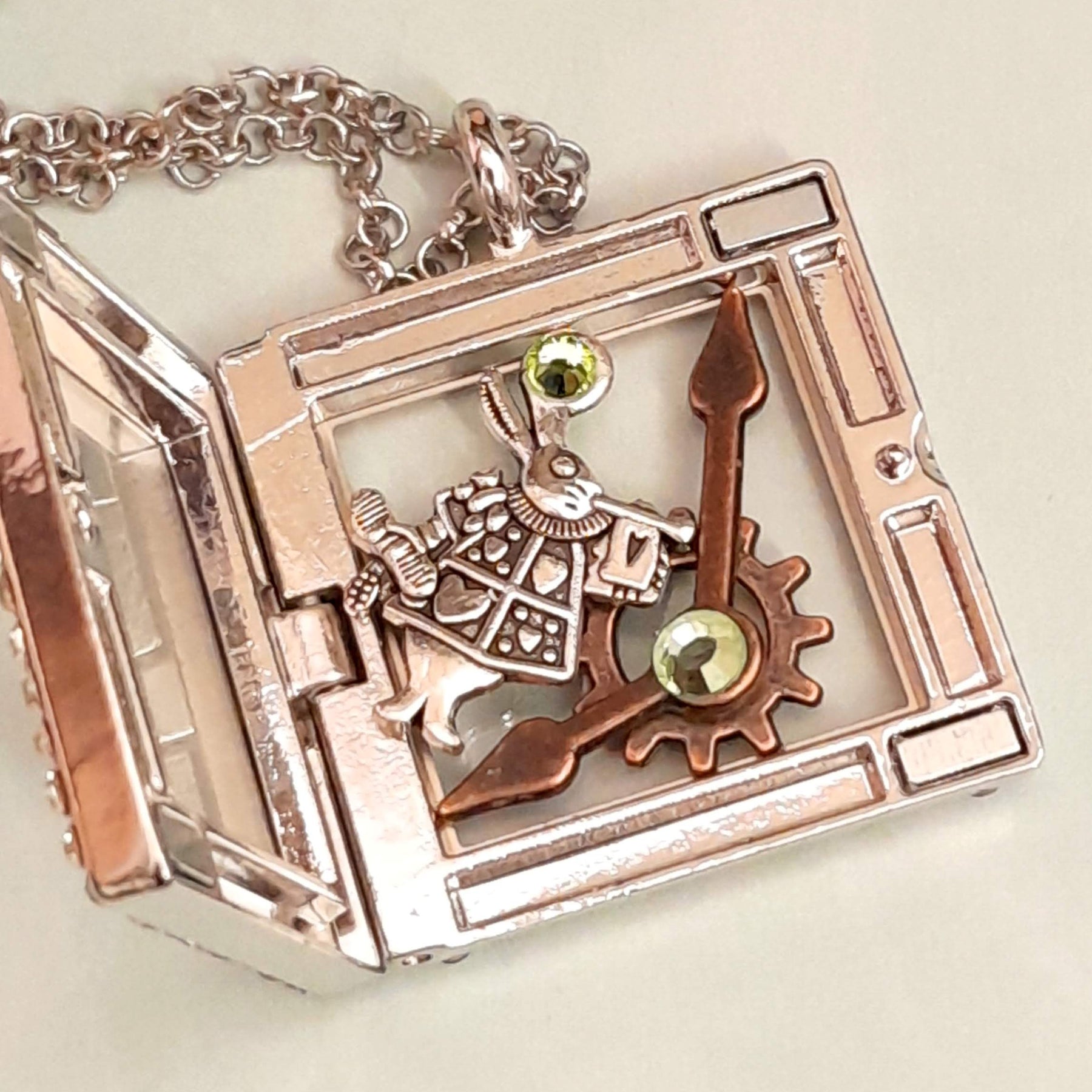 Magical fantasy Alice in Wonderland square locket necklace open showing White Rabbit, gear and clock hand charms inside with green Swarovski crystal accents,  chain, Victorian style vintage style