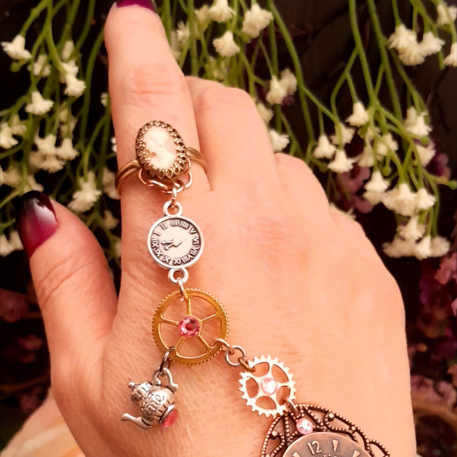 Alice in Wonderland steampunk hand chain slave bracelet worn on hand dark floral background cameo ring clock gears teapot Swarovski rose crystals Victorian style vintage style handmade Rachel Flam Design