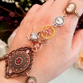 Alice in Wonderland steampunk hand chain slave bracelet worn on hand showing cameo ring clock disc gears teapot charm rose cameo beads Swarovski rose crystals Victorian style vintage style handmade Rachel Flam Design