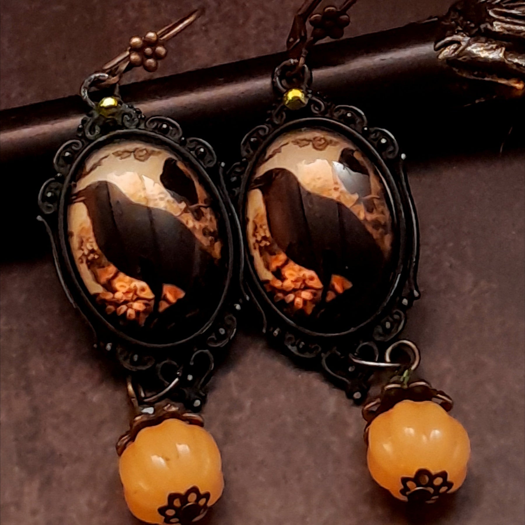 One-of-a-kind witchy earrings with black crows, warm autumn imagery, yellow Swarovski crystals, and dangling pumpkin details, Victorian style and vintage style magical fantasy jewelry by Rachel Flam Design