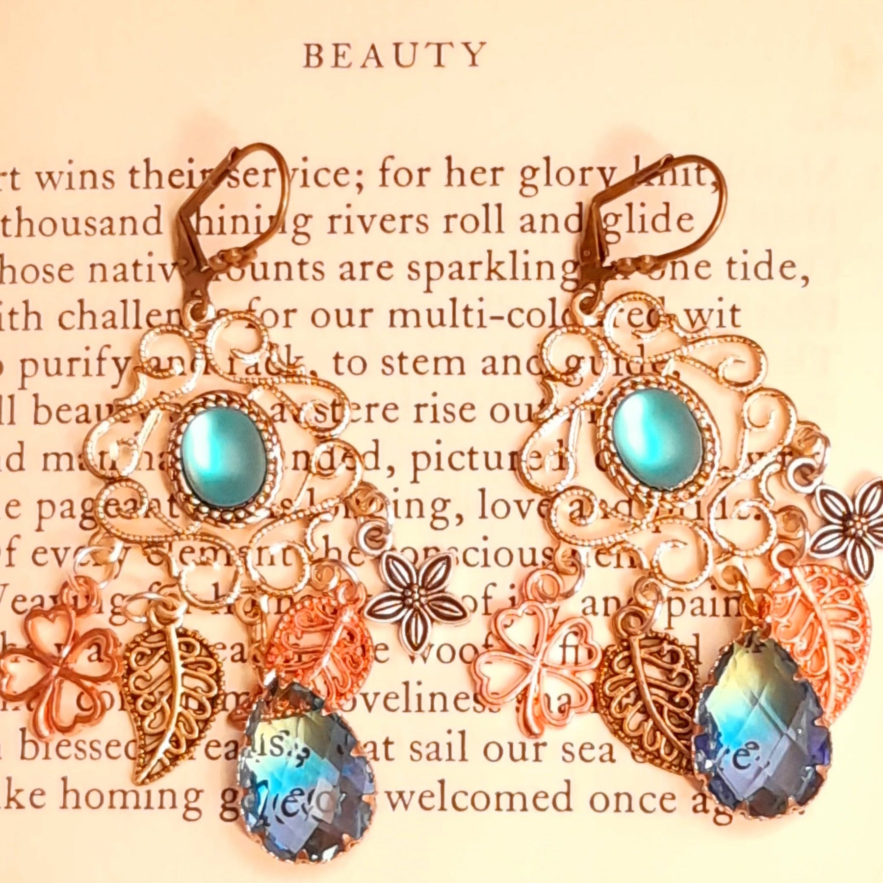 Vintage style and Victorian style chandelier earrings featuring turquoise cat eye centers, ornate botanical details, flowers, leaves, and faceted ombre glass drops by Rachel Flam Design