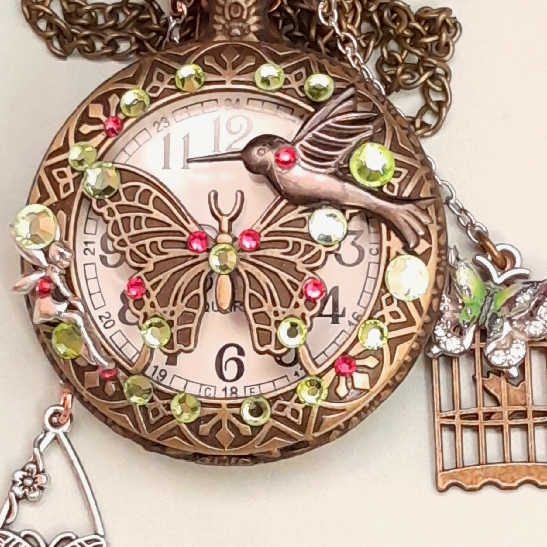 Handmade magical fantasy butterfly hummingbird pocketwatch necklace front with peridot green and pink Swarovski crystals, butterfly birdcage charms, antiqued brass, Victorian style vintage style