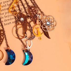 Victorian style and vintage style fantasy ear cuff details by Rachel Flam Design on an open book, showing cat and moon charms, feathers, wings and sparkling Swarovski crystals.