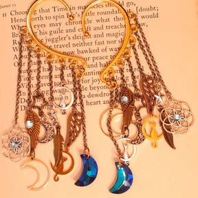 Victorian style and vintage style non pierced ear cuffs by Rachel Flam Design, embellished with Swarovski crystals and cascading moon, cat, star and feather charms, displayed on an open book.