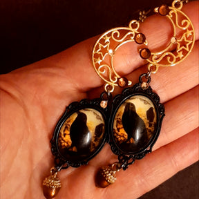 Long crow and crescent moon dangle earrings held in hand for scale with Swarovski crystals and acorn charms, Victorian style vintage style nature Halloween earrings, Rachel Flam Design