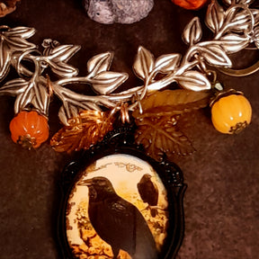 Detailed crow and pumpkin necklace with leafy branches, orange pumpkins, autumn foliage, raven artwork, and layered Swarovski crystal accents, Victorian style and vintage style magical fantasy jewelry by Rachel Flam Design