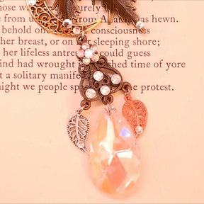 Rachel Flam Design Victorian style and vintage style fantasy necklace detail on a book page, showing a Swarovski® crystal flower, decorated openwork connector, leaf charms, and iridescent teardrop.