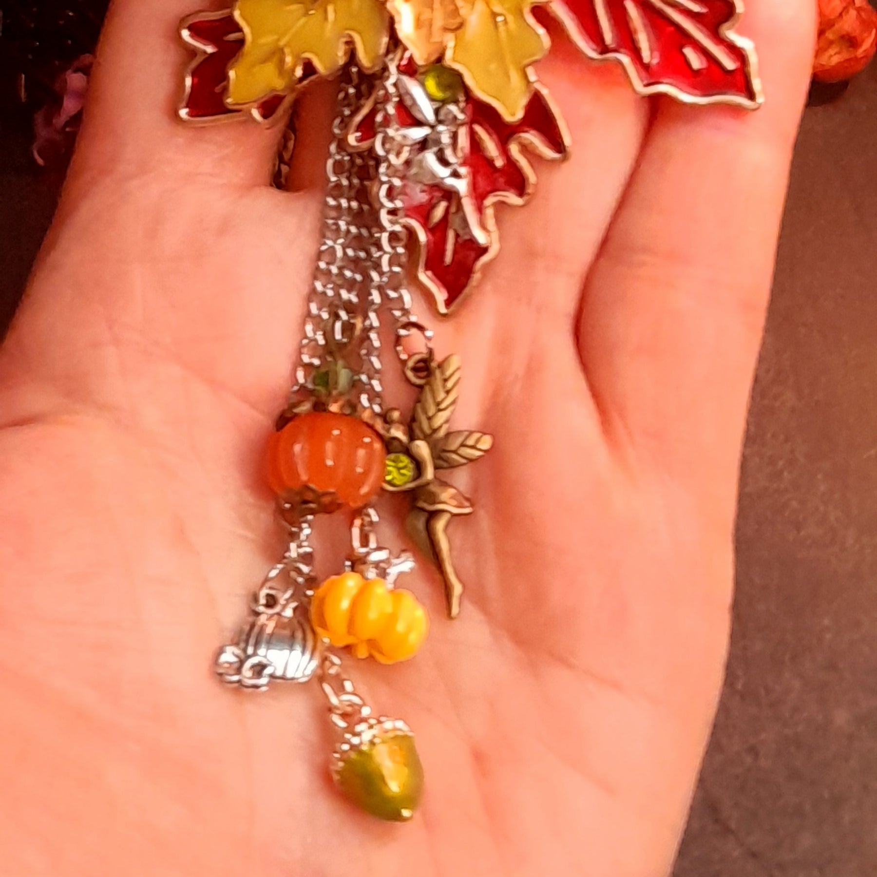 Close up of dangling silver fairy, orange pumpkin, yellow pumpkin and green acorn charms on cascading chains, Victorian style vintage style fantasy brooch by Rachel Flam Design