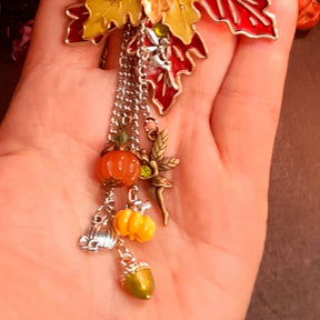 Close up of dangling silver fairy, orange pumpkin, yellow pumpkin and green acorn charms on cascading chains, Victorian style vintage style fantasy brooch by Rachel Flam Design