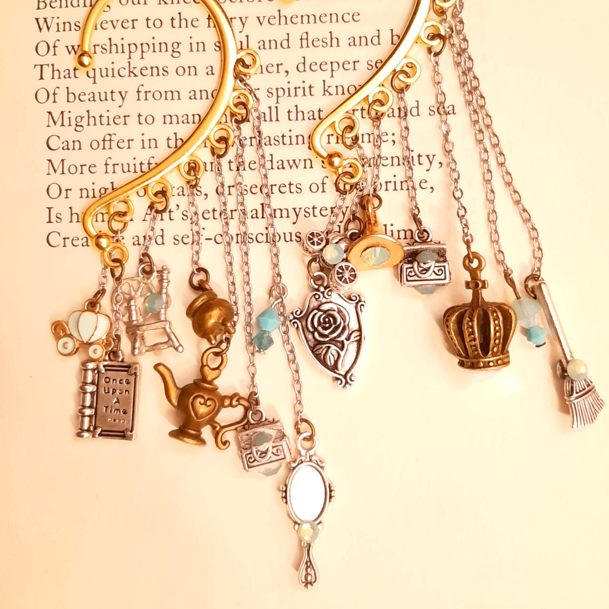 Victorian style vintage style fairy tale ear cuff for non-pierced ears featuring Once Upon a Time book, pumpkin carriage, crown, oval mirror, family crest, treasure chests, genie lamp, spinning wheel, broom, and cauldron charms with Pacific Opal Swarovski crystals, magical fantasy jewelry