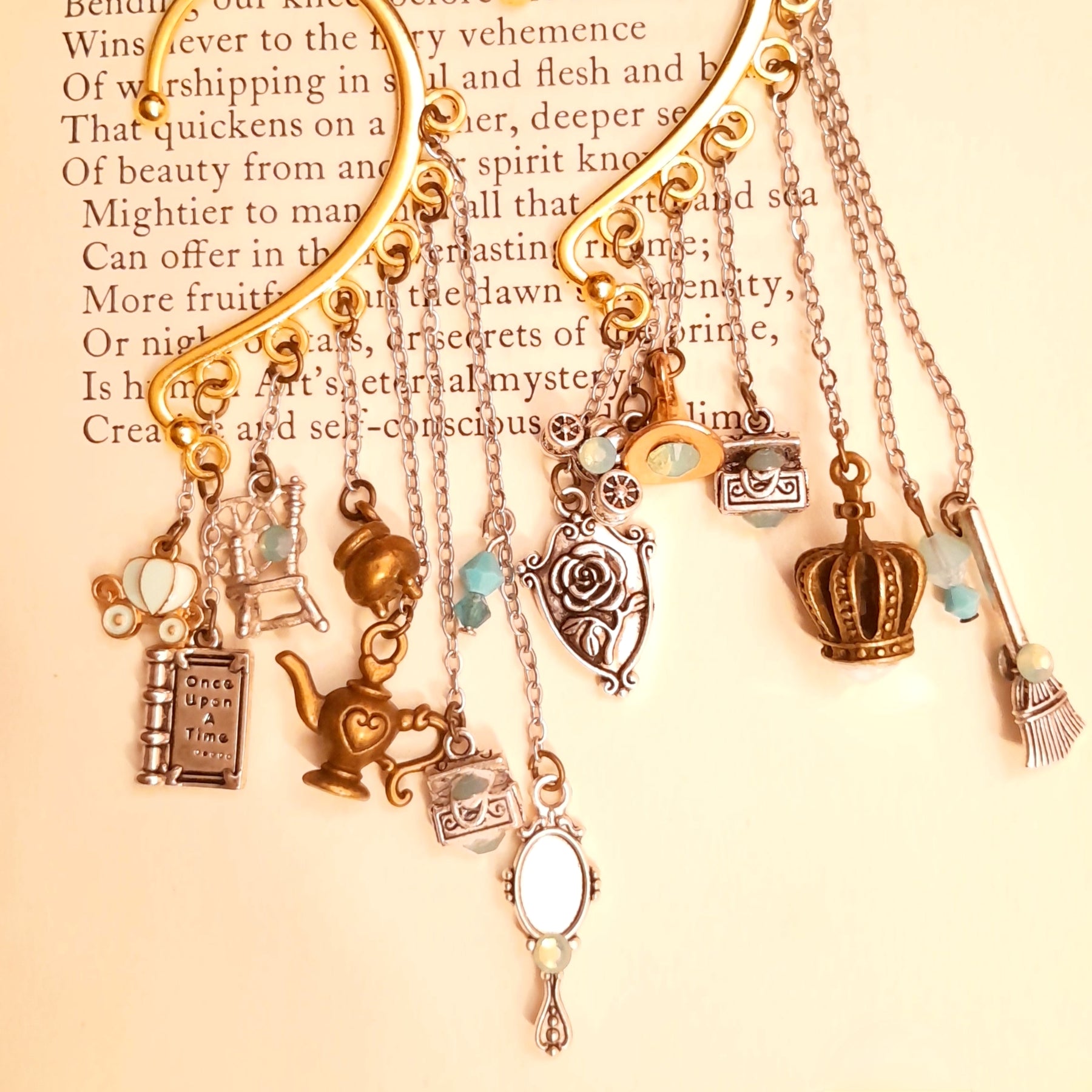 Victorian style vintage style fairy tale ear cuff for non-pierced ears featuring Once Upon a Time book, pumpkin carriage, crown, oval mirror, family crest, treasure chests, genie lamp, spinning wheel, broom, and cauldron charms with Pacific Opal Swarovski crystals, magical fantasy jewelry