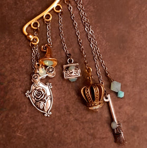 Victorian style vintage style fairy tale ear cuff for non-pierced ears with treasure chests, genie lamp, Once Upon a Time book, pumpkin carriage, crown, oval mirror, family crest, spinning wheel, broom, and cauldron charms, Pacific Opal Swarovski crystals, magical fantasy jewelry