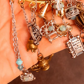 Victorian style vintage style fairy tale ear wrap for non-pierced ears featuring spinning wheel, broom, cauldron, Once Upon a Time book, pumpkin carriage, crown, oval mirror, family crest, treasure chests, and genie lamp charms with Pacific Opal Swarovski crystals, handmade fantasy jewelry
