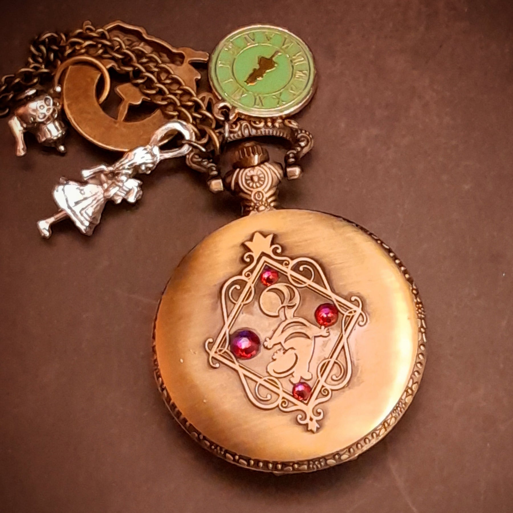 Fantasy pocket watch necklace featuring teapot and clock charms inspired by Alice in Wonderland cheshire cat
