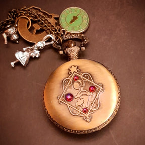 Fantasy pocket watch necklace featuring teapot and clock charms inspired by Alice in Wonderland cheshire cat
