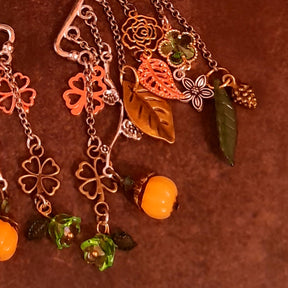 Victorian style and vintage style ear cuff detail by Rachel Flam Design, with green Swarovski crystals, cascading flower links, textured leaves and an orange pumpkin drop.