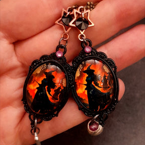 Halloween handmade witch portrait earrings held in hand with star accents, black and purple Swarovski crystals, ornate frames and mismatched charms in Victorian style and vintage style by Rachel Flam Design
