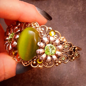Adjustable botanical bracelet with luminous green cat’s-eye centerpiece, floral details, and Swarovski crystals, Victorian style vintage style magical jewelry