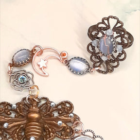 Magical fantasy bee hand chain slave bracelet  on wrist close up of bracelet portion showing blue floral cameo open rose charm and rose bud charms with blue Swarovski crystals Victorian style vintage style