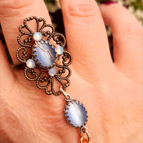 Handmade fantasy bee hand chain slave bracelet  flat lay close up of dramatic bee centerpiece filigree backing crescent moon charm and open rose charm with blue Swarovski crystals Victorian style vintage style