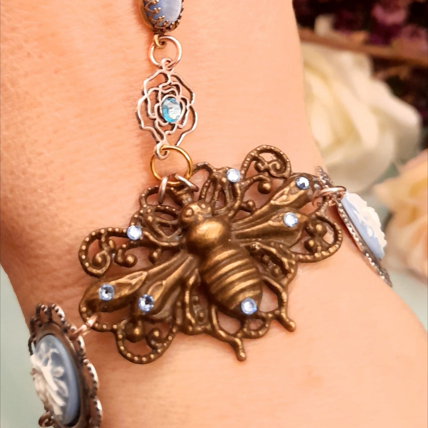 Magical fantasy bee hand chain slave bracelet on wrist close up of blue and white 3D floral cameo and bee centerpiece with Swarovski crystals Victorian style vintage style