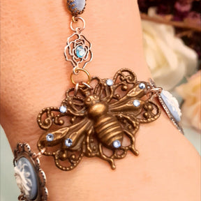 Magical fantasy bee hand chain slave bracelet on wrist close up of blue and white 3D floral cameo and bee centerpiece with Swarovski crystals Victorian style vintage style