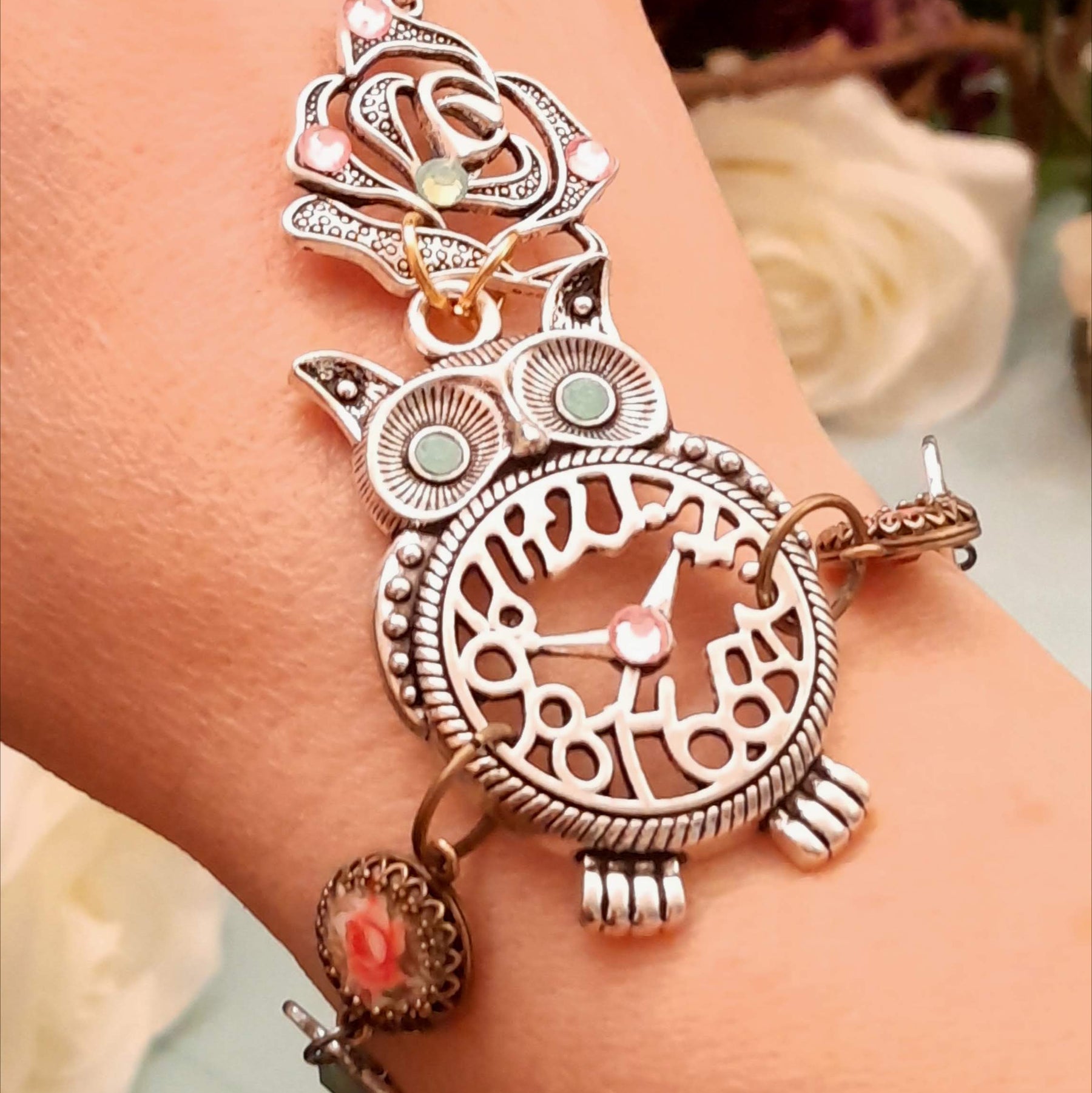 Handmade fantasy owl hand chain worn on wrist close up of owl centerpiece and open rose charm with mint and pink Swarovski crystals Victorian style vintage style