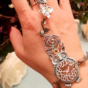 Handmade fantasy owl hand chain on wrist close up of owl centerpiece with mint opal eyes and pink Swarovski crystals Victorian style vintage style