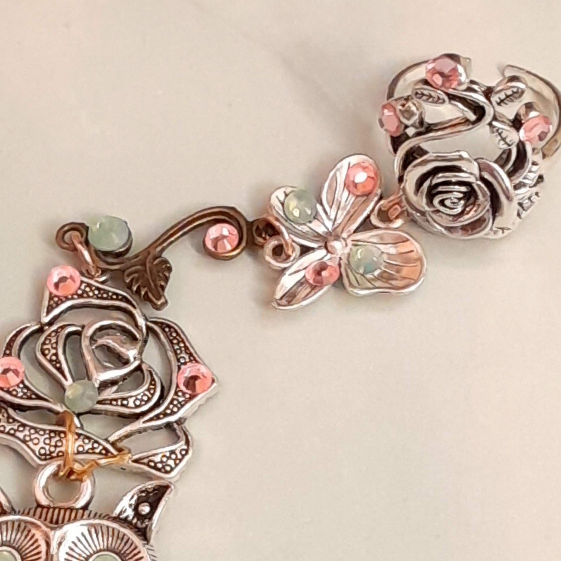 Handmade fantasy owl hand chain on hand close up of adjustable floral rose ring and butterfly charm with pink and mint Swarovski crystals Victorian style vintage style