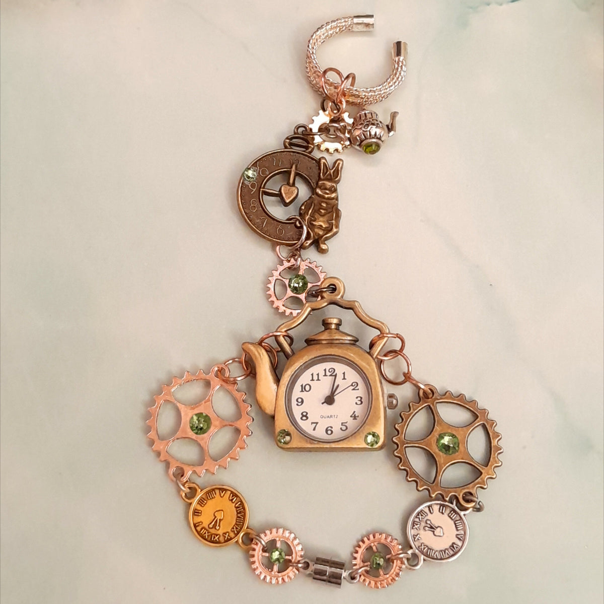 Magical fantasy hand chain teapot watch Alice in Wonderland with green Swarovski crystals flat lay front view, Victorian style vintage style