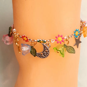 Handmade celestial fairy charm anklet featuring fairy figures, ornate crescent moon, star charms, multicolor enamel daisy flowers, and colorful flower beads with leaf accents, Victorian style vintage style