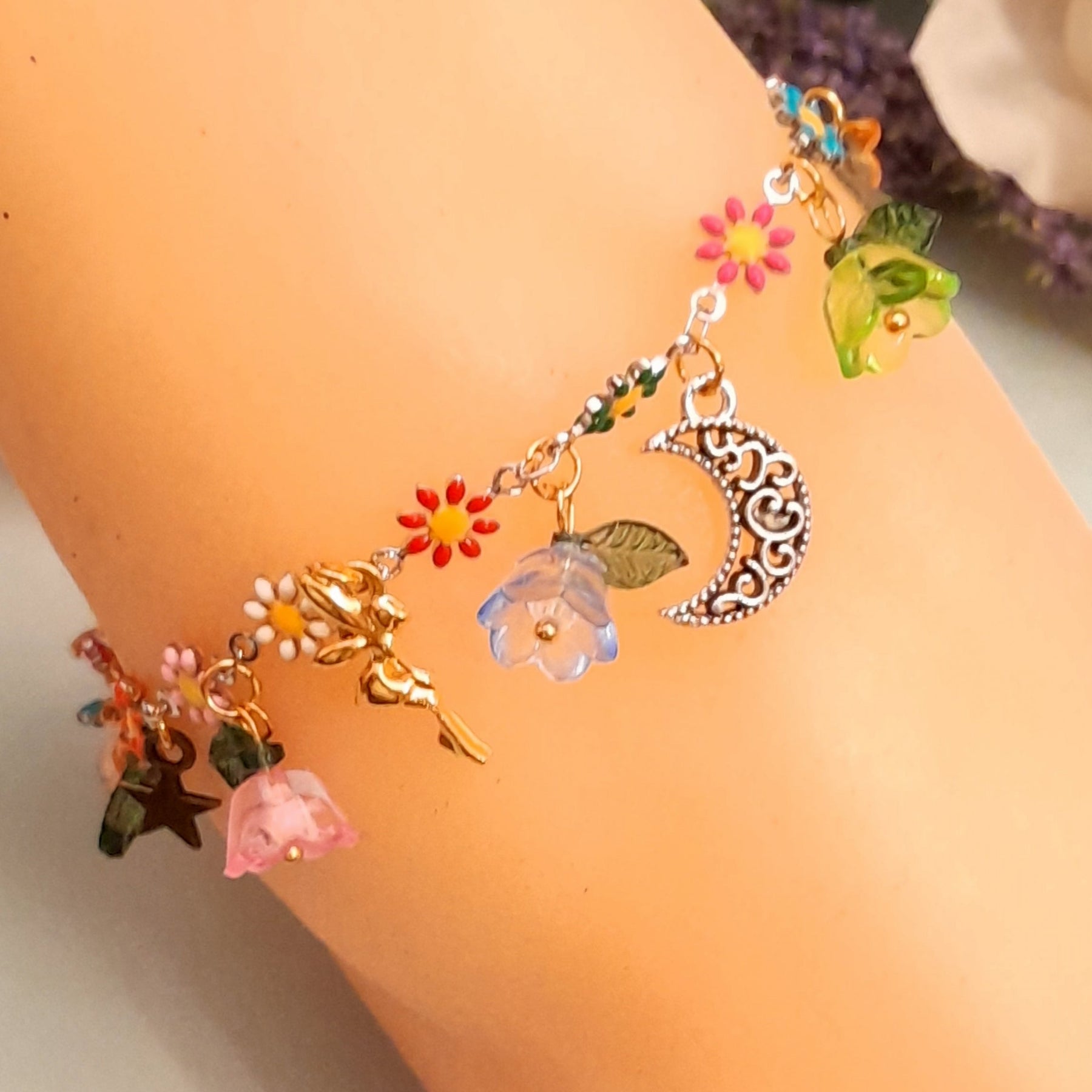 Full view of handmade rainbow fairy charm anklet with fairy figures, crescent moon, star charms, multicolor enamel daisy flowers, and colorful flower beads with leaf charms, Victorian style vintage style fantasy jewelry