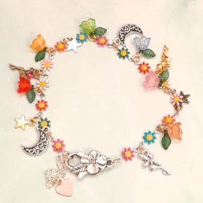 Handmade rainbow fairy moon charm anklet with fairy figures, crescent moon, star charms, multicolor enamel daisy flowers, flower beads, and leaf charms worn on ankle, Victorian style vintage style fantasy jewelry