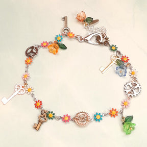 Handmade rainbow steampunk charm anklet with vintage keys, gear charms, multicolor enamel daisy flowers, and crystal flower beads worn on ankle, Victorian style vintage style fantasy jewelry
