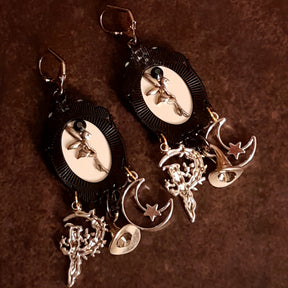 Handmade raven and skull earrings shown in hand with smoky crystal accents, crescent moon charms, witch hat details, and detailed witch figures, Victorian style and vintage style fantasy jewelry by Rachel Flam Design