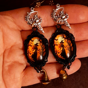 Handmade witchy fairy earrings with framed autumn witch artwork, orange crystal sparkle, crescent moon, broom, witch hat, and cauldron details, Victorian style and vintage style fantasy jewelry by Rachel Flam Design