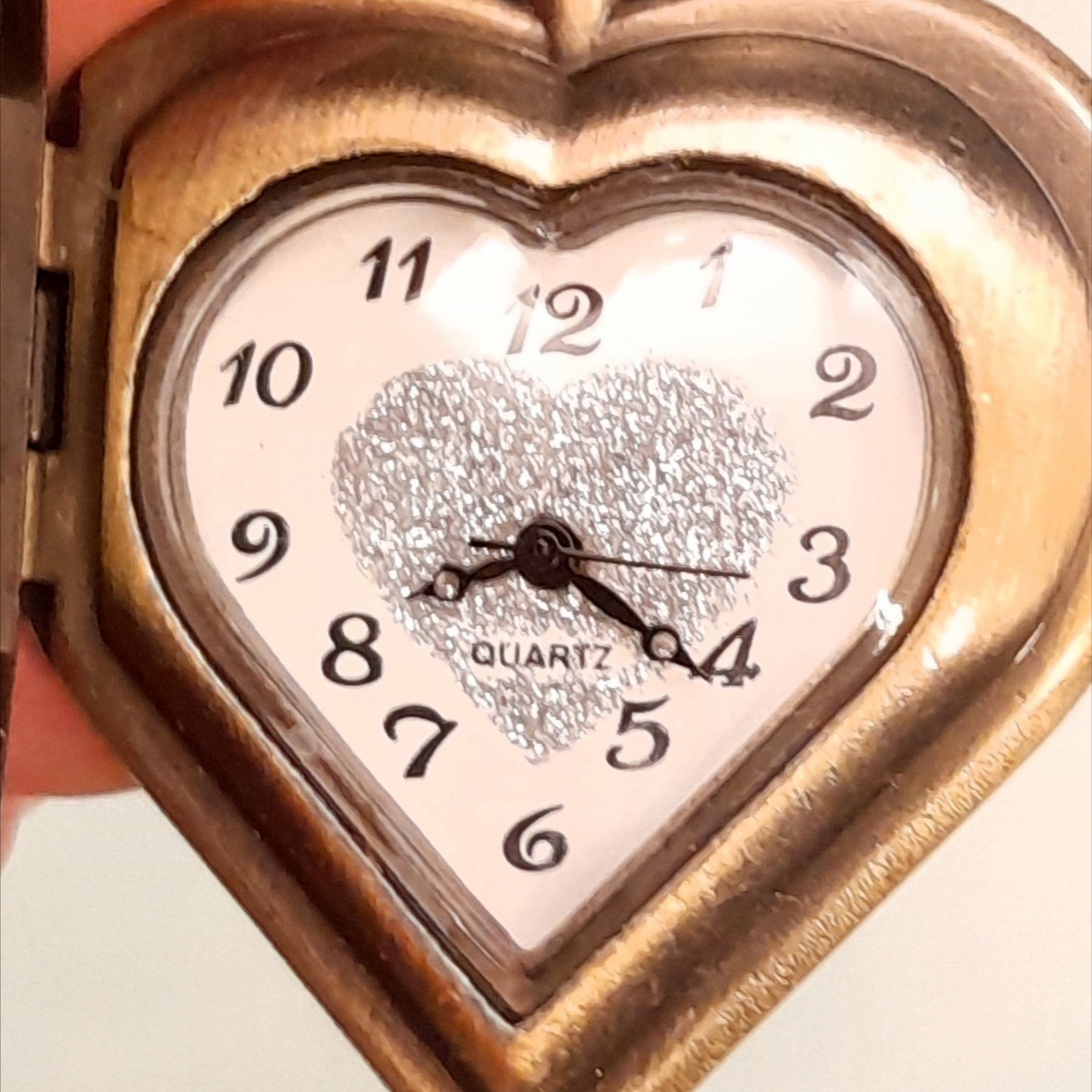 Close up of magical fantasy heart pocket watch necklace open quartz watch face with silver glitter heart center, antiqued brass, Victorian style vintage style