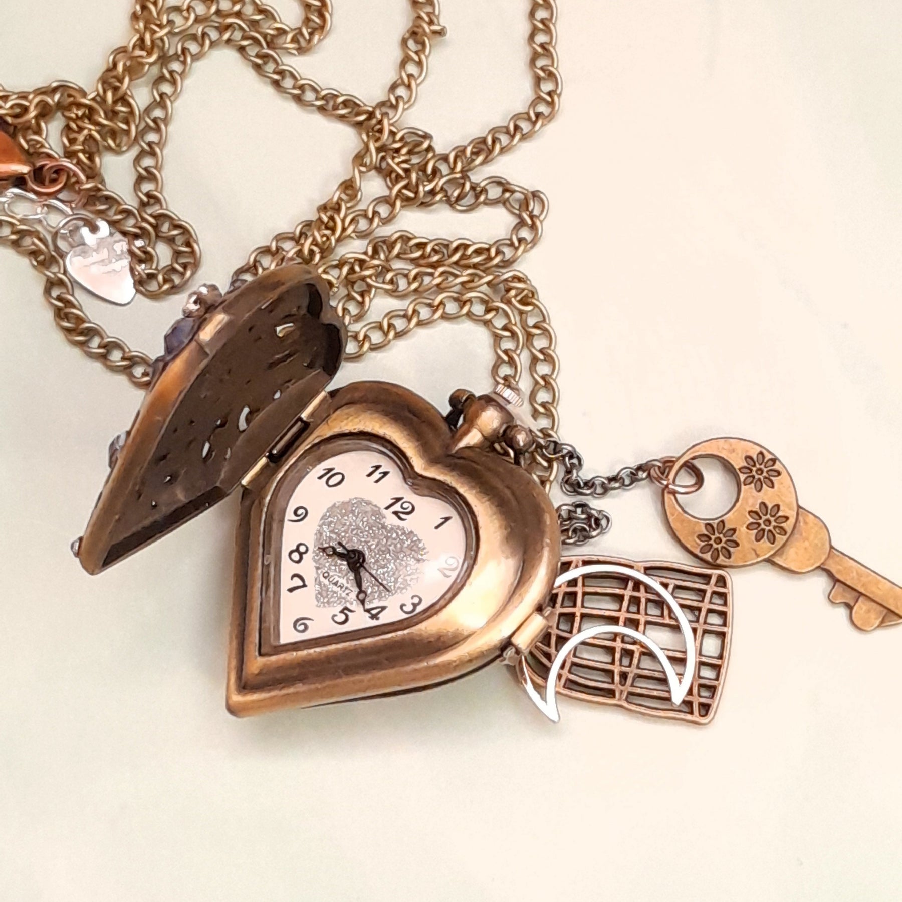 Close up of handmade magical fantasy heart pocket watch necklace with filigree detail, lavender and clear Swarovski crystals, antiqued brass, Victorian style vintage style